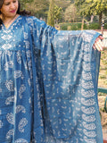 A woman outdoors showcases the wide sleeve of The Reet Set | Indigo Block print, adorned with white floral and paisley patterns. She stands amidst lush greenery and trees.